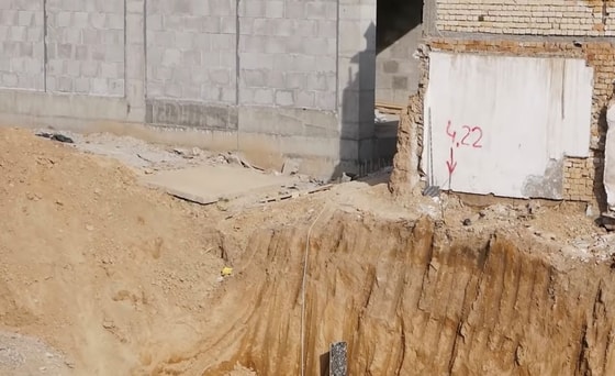 Котлован и рядом стоящий жилой дом